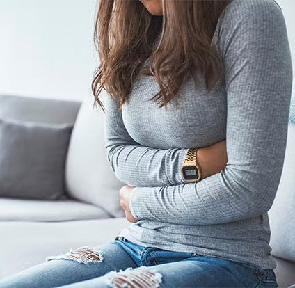 Mujer sujentando con dolor su adbomen.