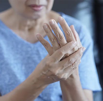 Mujer mayor sujetando su mano en señal de dolor.