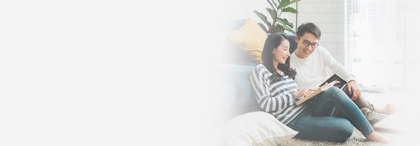 Asian couple sitting on the floor reading a book