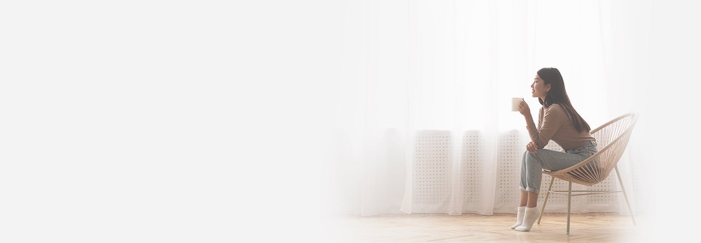 young girl sitting in the chair enjoying coffee in front of window