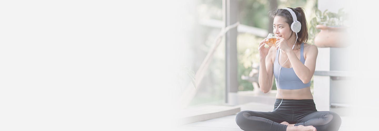 Asian beautiful woman drinking hot tea and wearing headphones while doing meditation