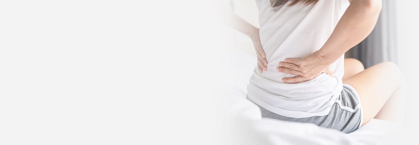 Woman suffering from backache sitting on the bed