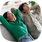 Peaceful young Asian couple relaxing on sofa with their hands behind heads