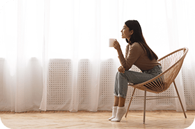 young girl sitting in the chair enjoying coffee in front of window