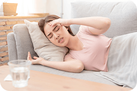 Young beautiful Asian woman on sofa having headache