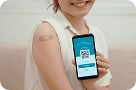 Asian woman smiling while holding Digital Covid-19 vaccine passport on mobile phone