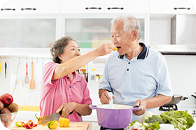 happy senior couple cooking in kitchen