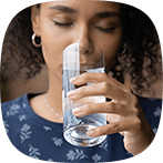 Kvinna med mörkt lockigt hår dricker ett glas vatten