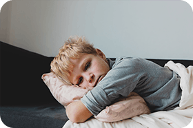 Trött pojke kramar kudde