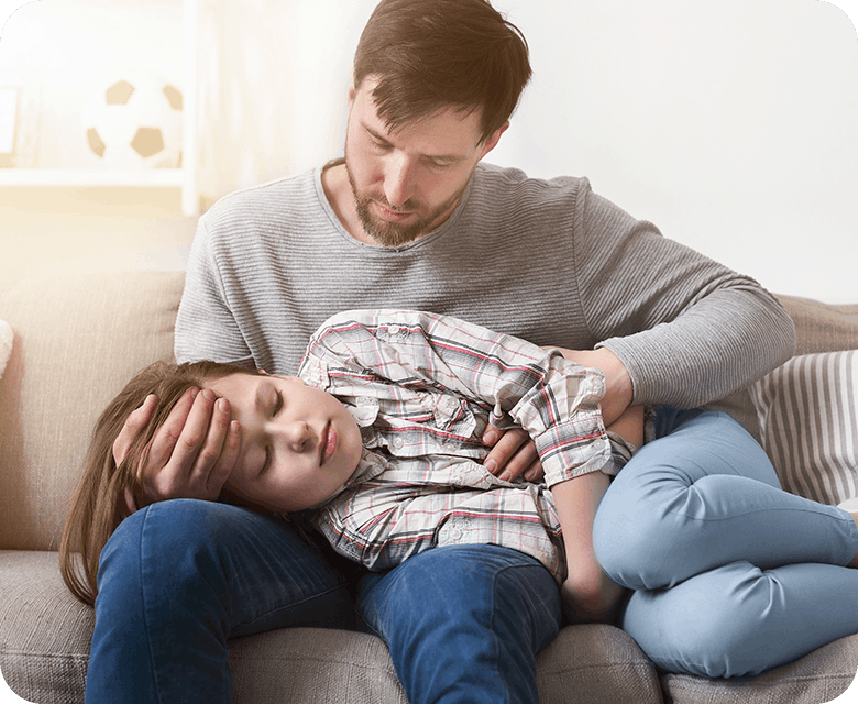 Pappa håller om förkyld dotter med feber