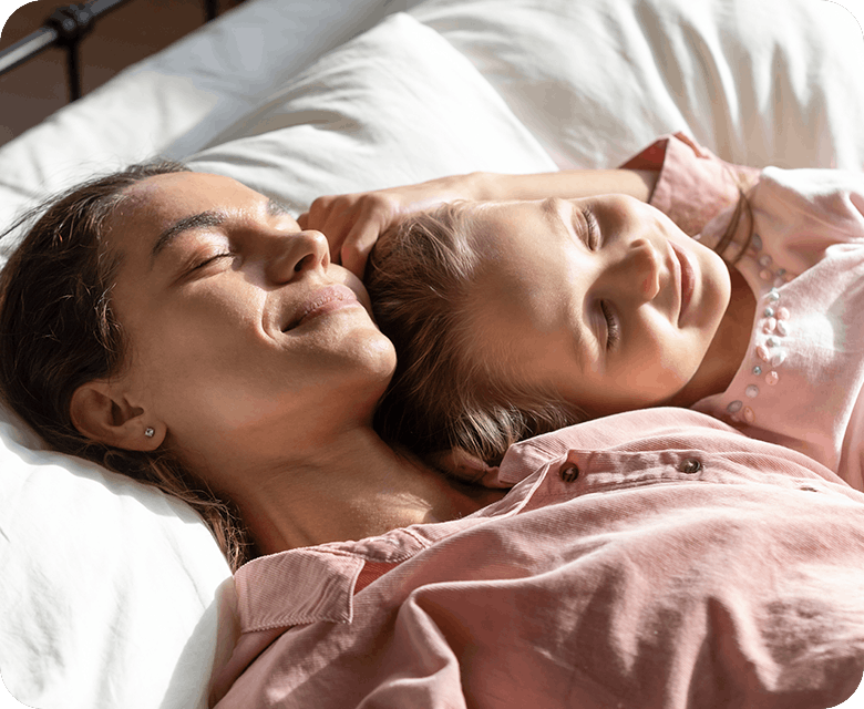 Mamma myser med sin dotter i säng
