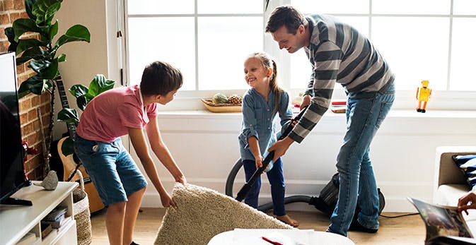 Børn hjælper deres far med at rengøring af tæppe