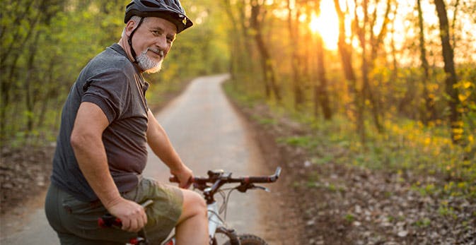 Ældre mand på cykeltur i skoven ved solopgang