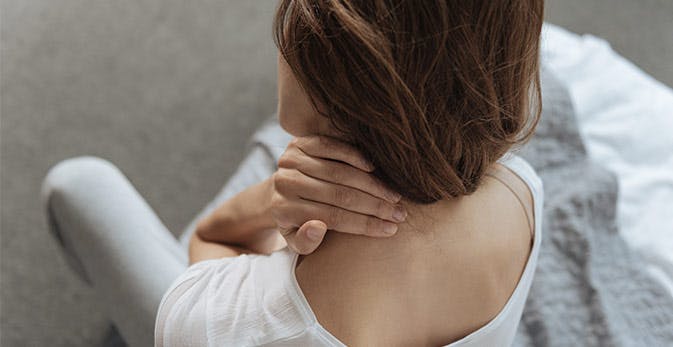 Kvinde masserer smertepunkt i nakken