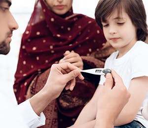A doctor checking a kid's temperature