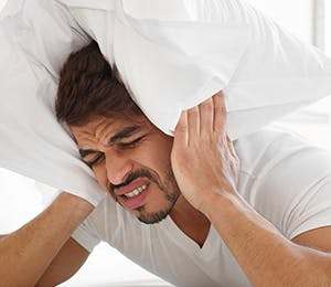 A man in bed suffering from an intense migraine