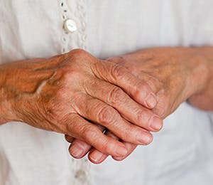An old woman's right hand holding her left hand