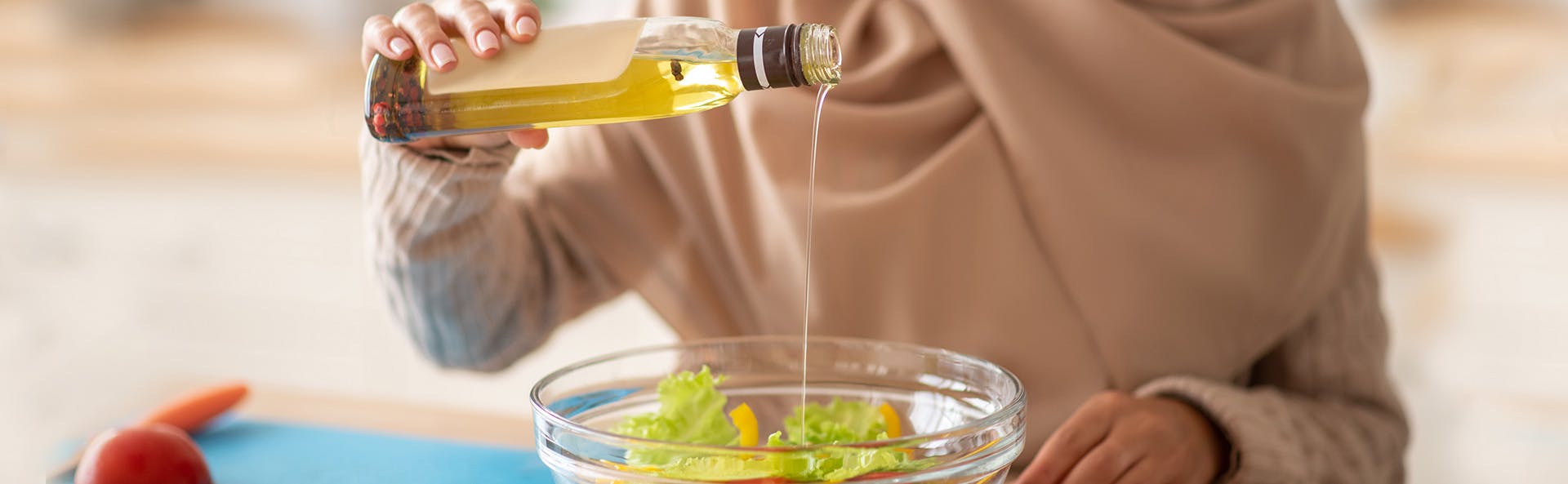 A woman adding oil to her salad