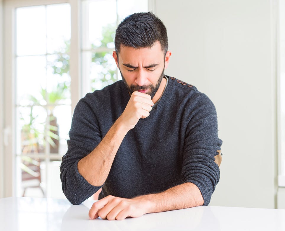 A man coughing and suffering from body aches A man coughing and suffering from body aches