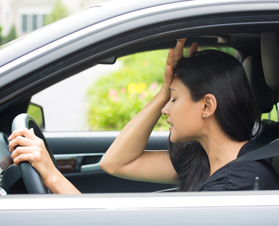 A woman driving and dealing with a headache