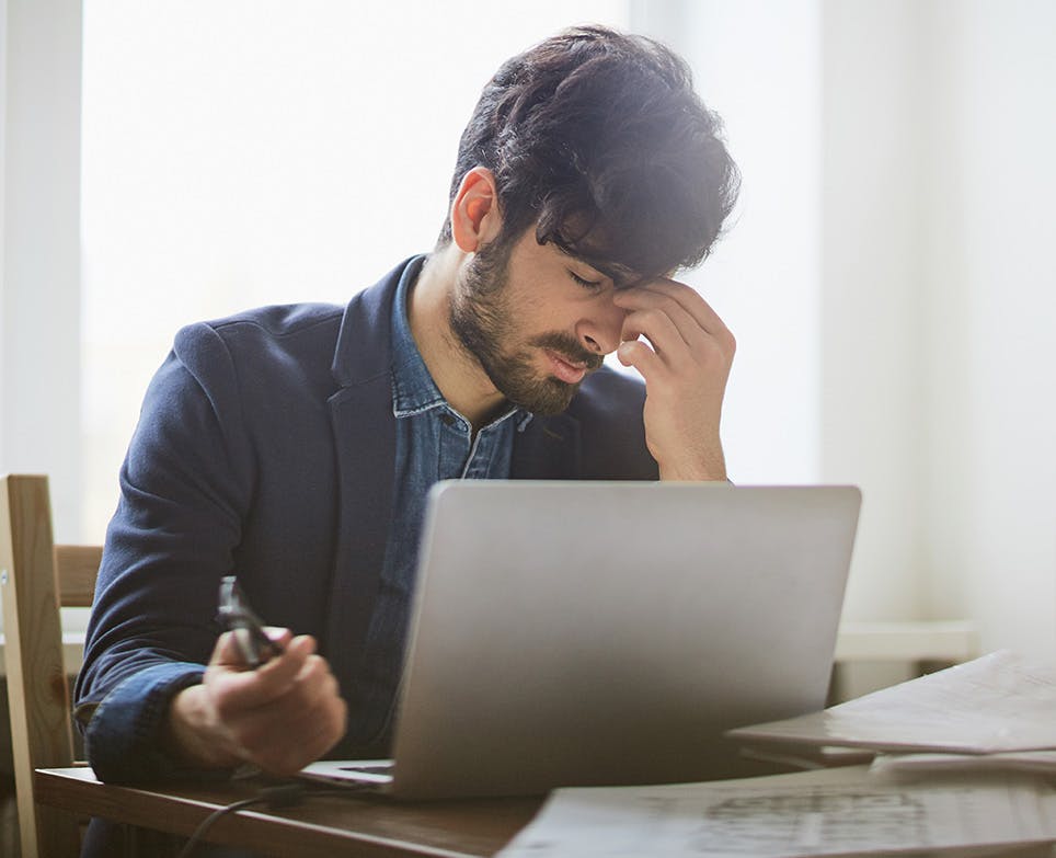 A man working on his computer while dealing with a migraine