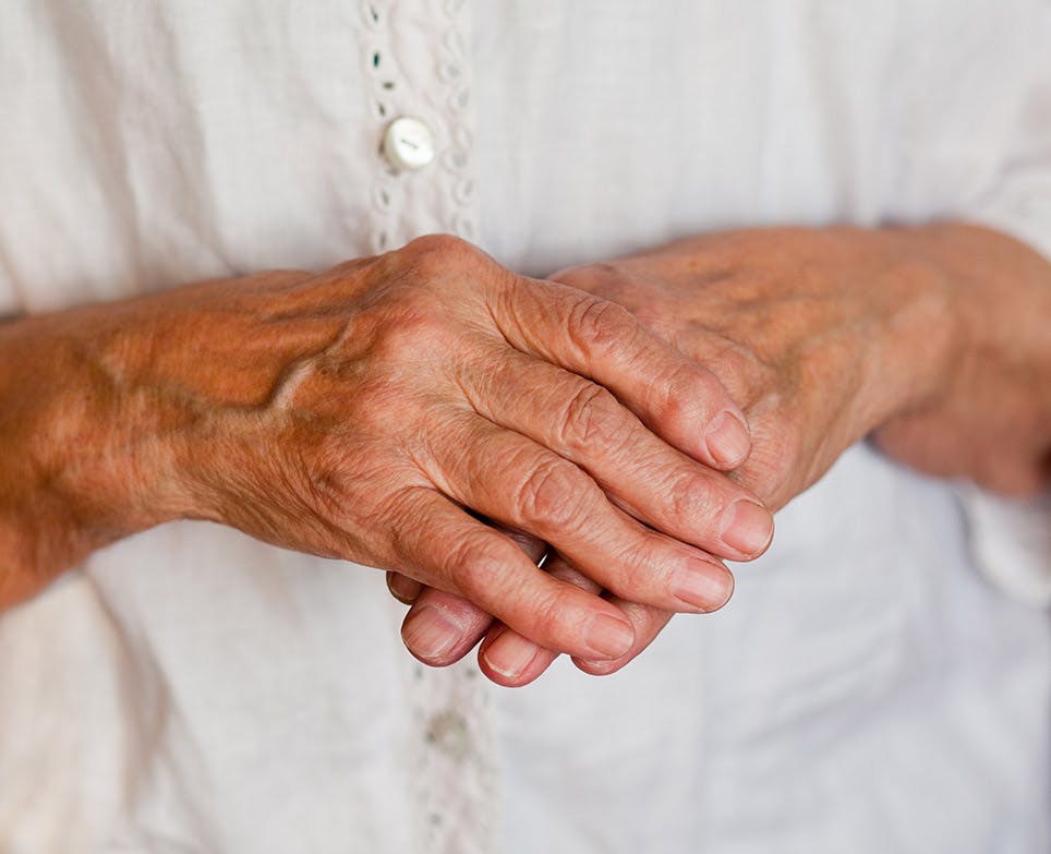 An old woman's right hand holding her left hand