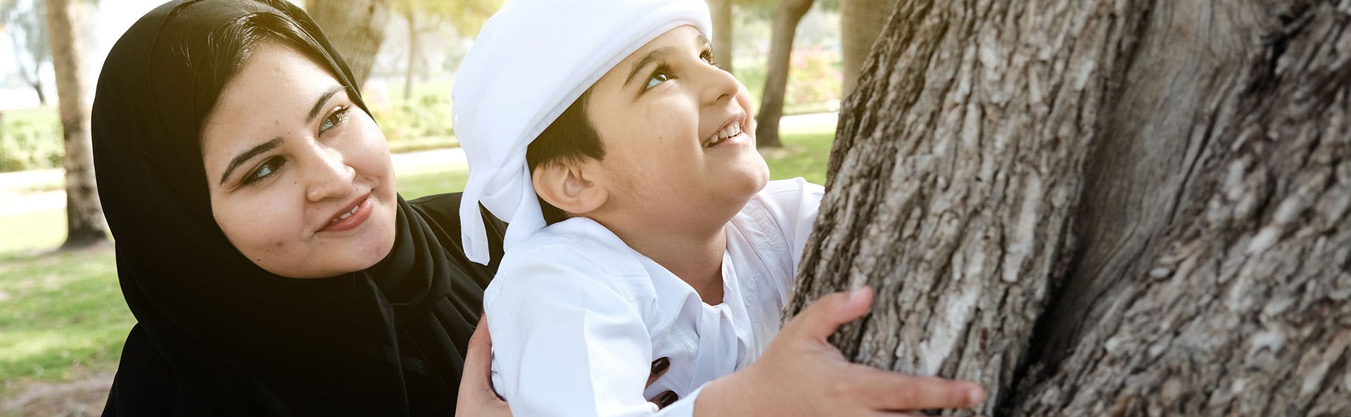 A mother holding her son as he climbs a tree A mother holding her son as he climbs a tree