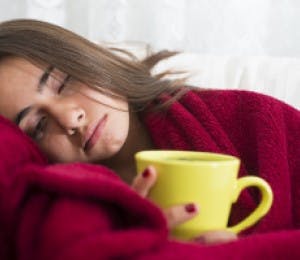 Woman with flu symptoms having a hot drink. 