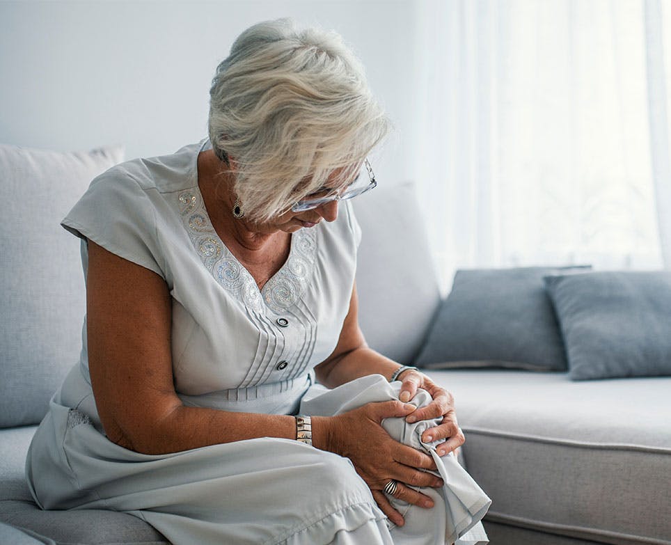 Older woman grabbing her knee in pain. 