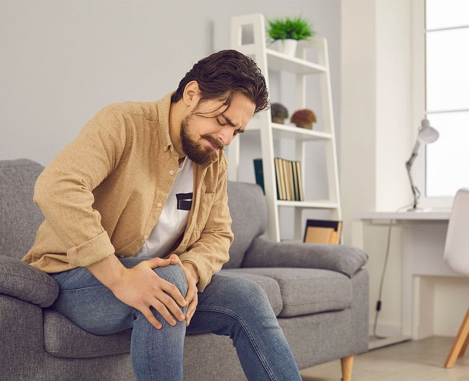 Young man holding his sore knee. 