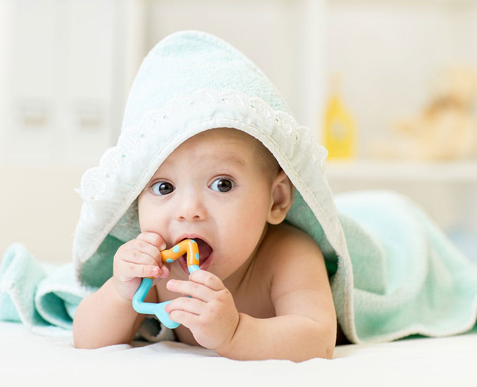 Baby biting a teething toy after a bath. Baby biting a teething toy after a bath.