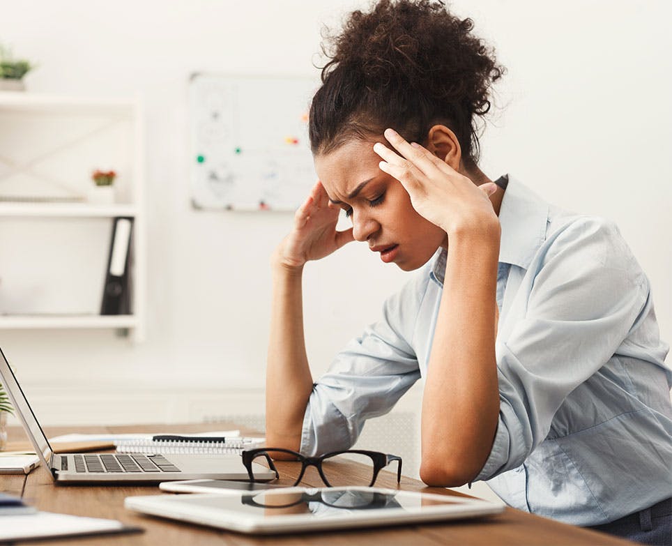 Young woman in pain holding her head from the sides. 