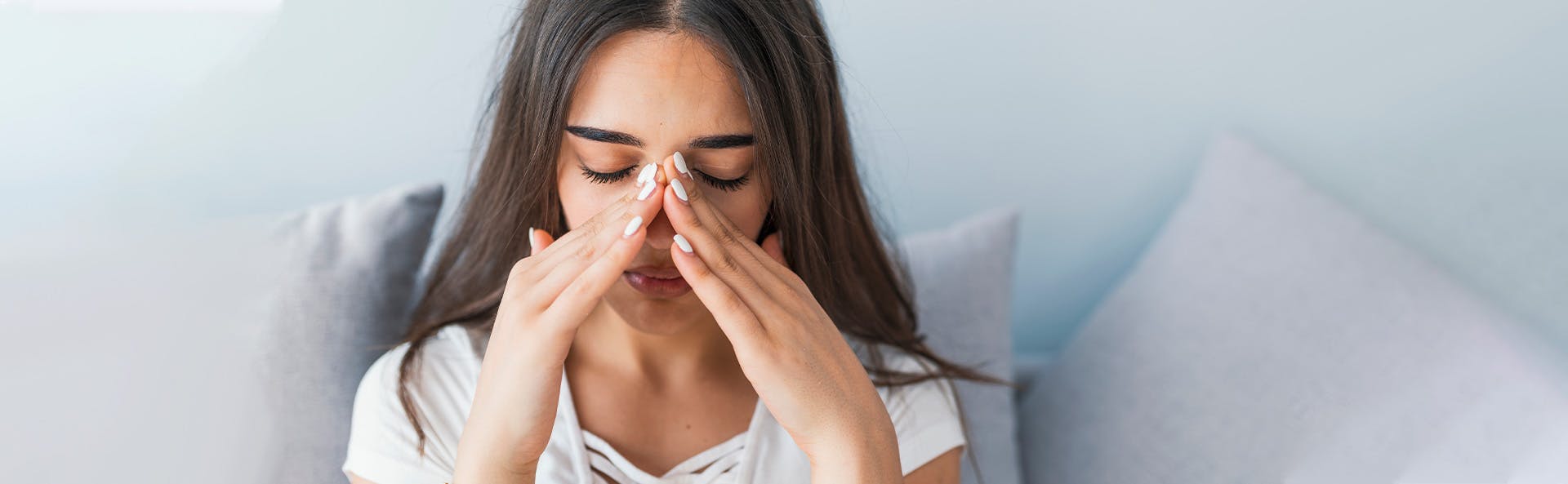 Young woman grabbing her nose to relief the pain. 