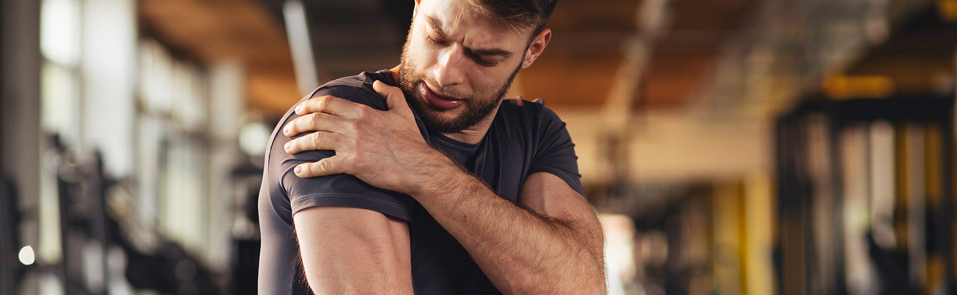 Young man holding his sore arm after exercising. 