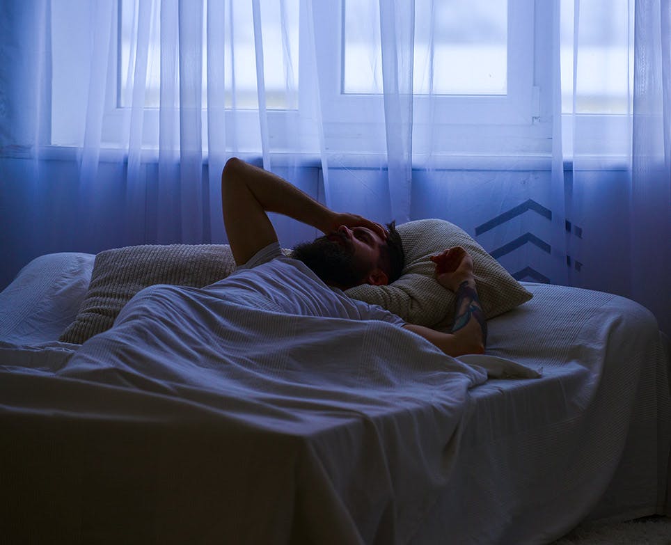 Man lying on his bed with a headache. 