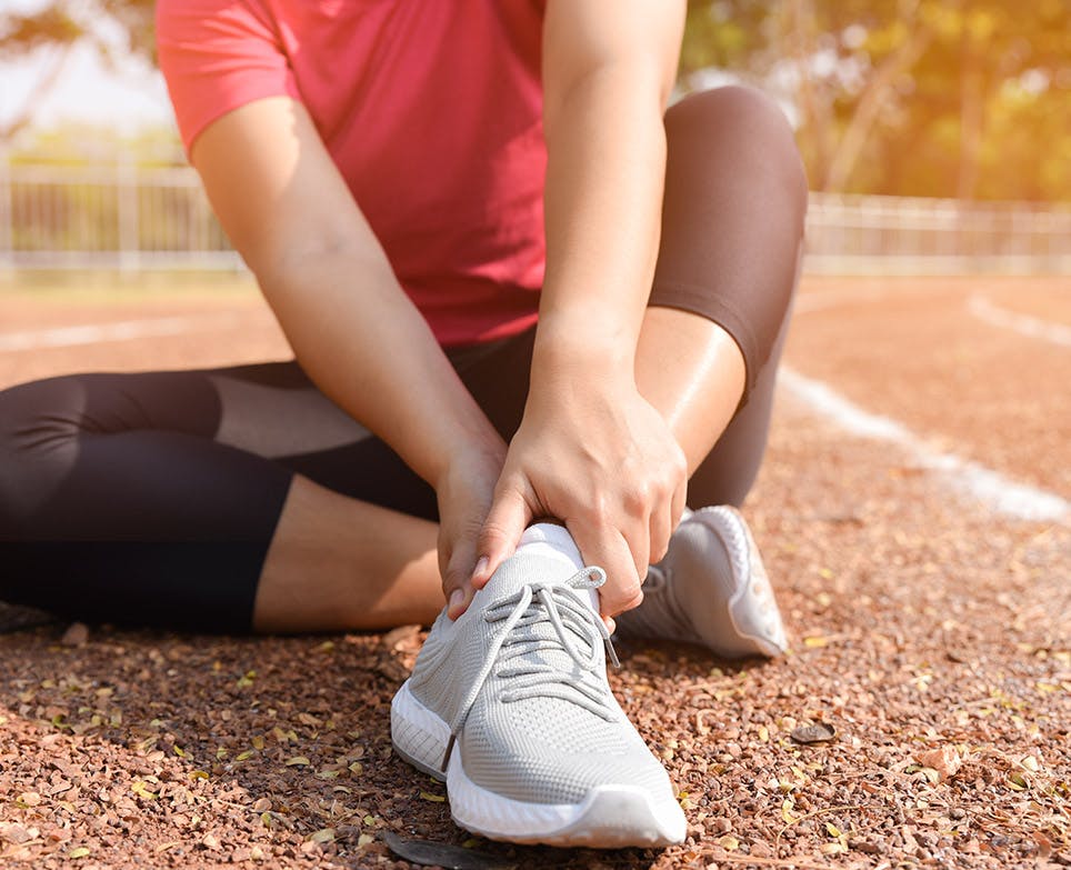 Woman holding her aching ankle. 