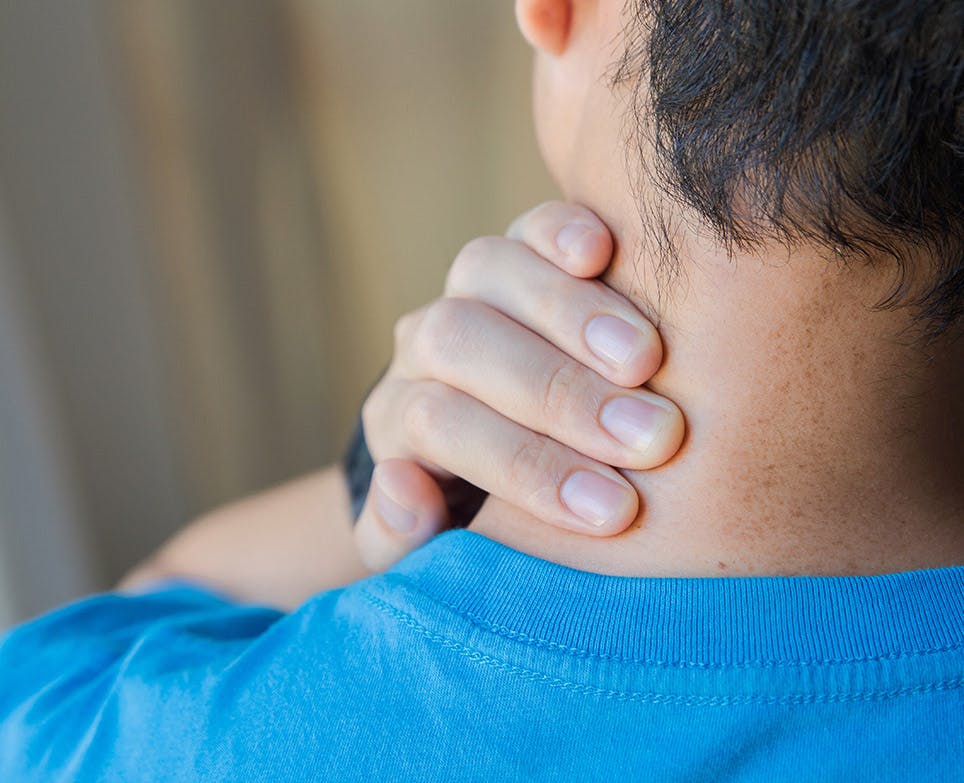 Man grabbing the back of his neck in pain. 