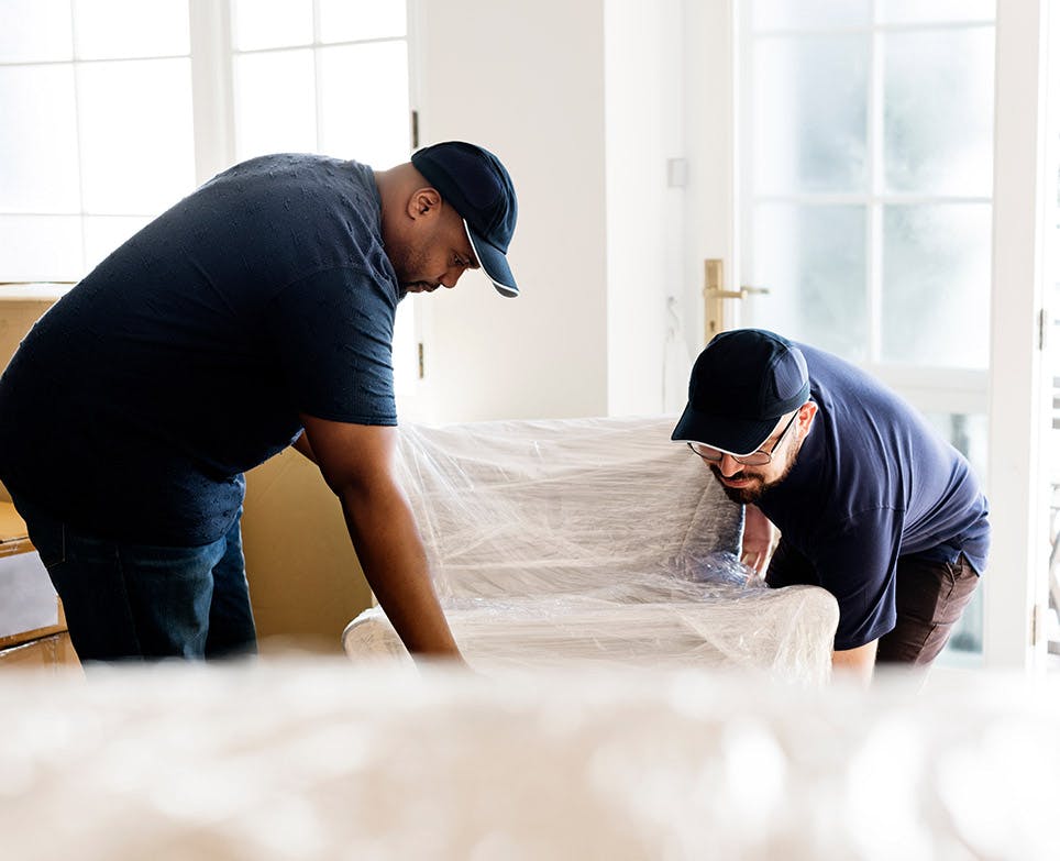 Two men lifting a couch. 