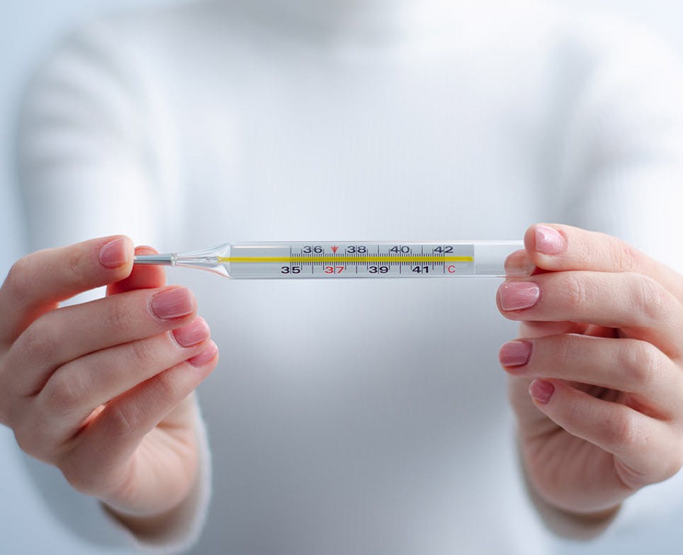 Woman checking and holding a traditional thermometer. 