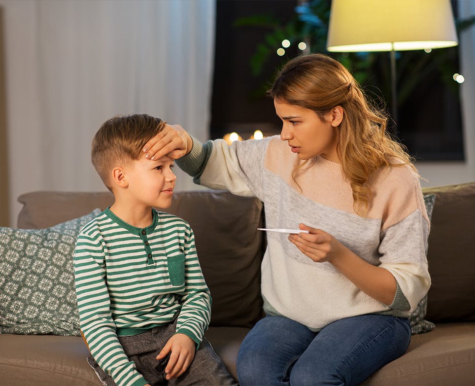 Mother taking her son's temperature with a thermometer. 