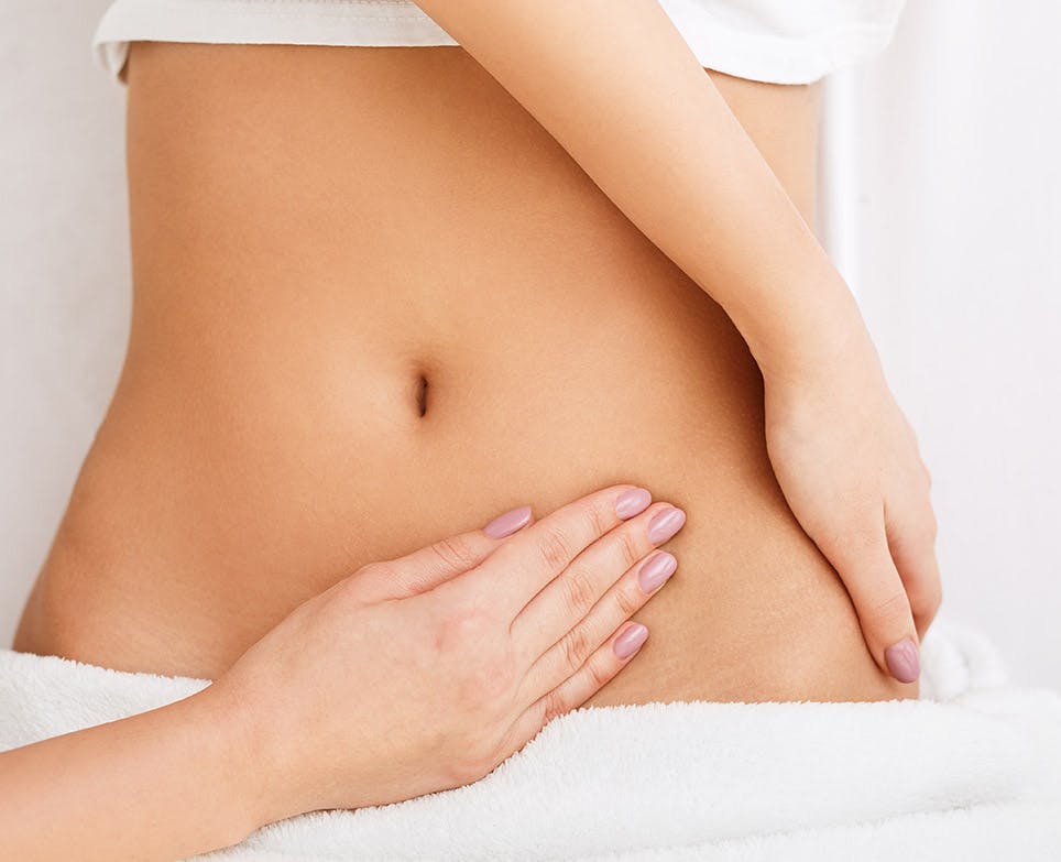 Massage into a woman's abdomen. 