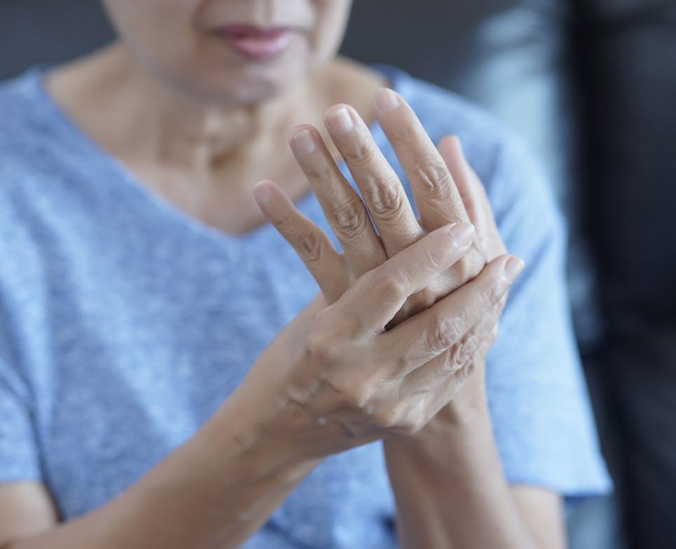 Older woman rubbing her aching hand. 