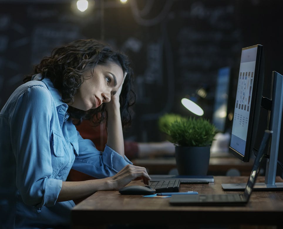 Woman in front of the computer holding her head. 