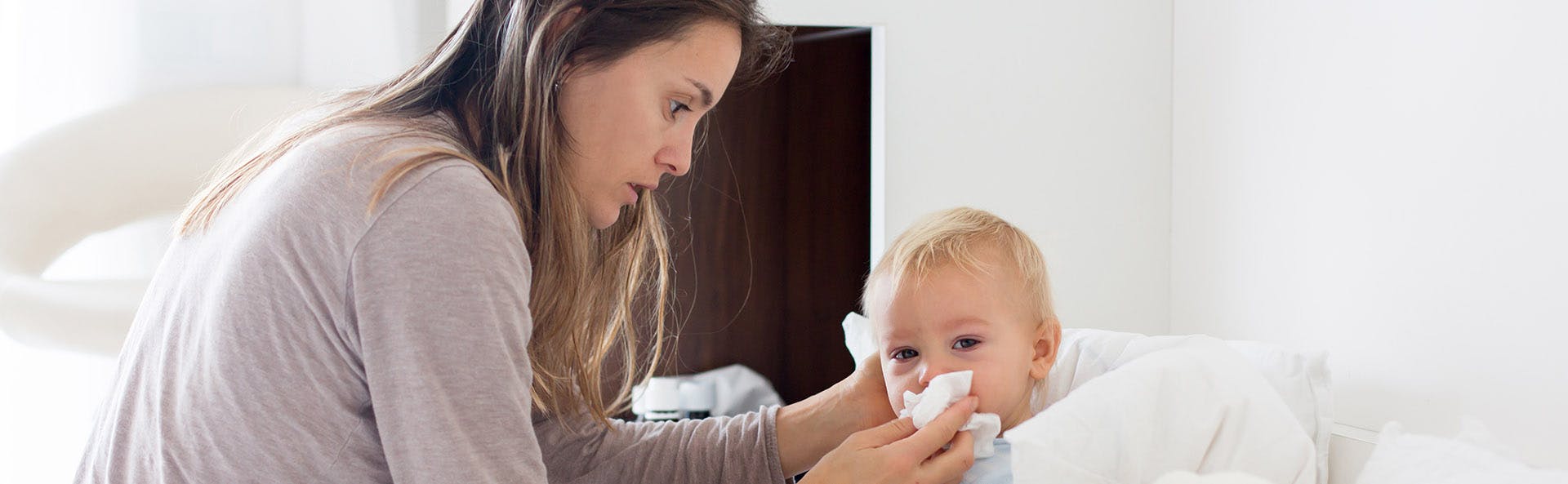 Mother claening her son's nose. 