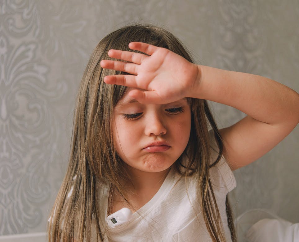 Little girl feeling her temperature by touching her forehead. 