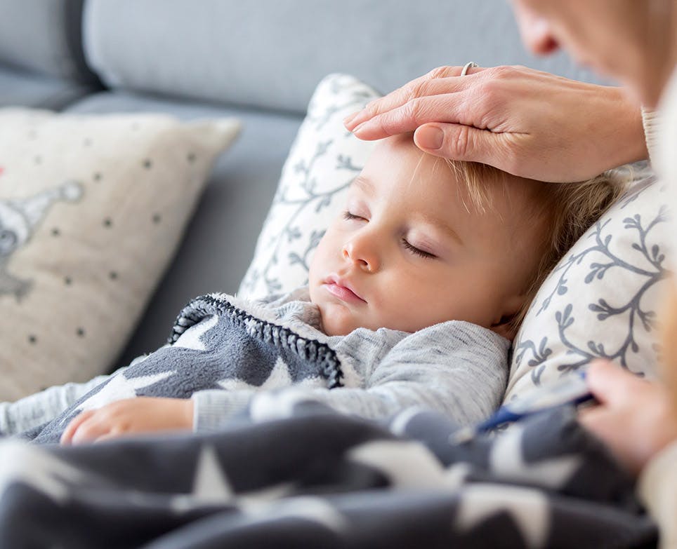 Mother feeling her daughter's temperature by touching her forehead.  