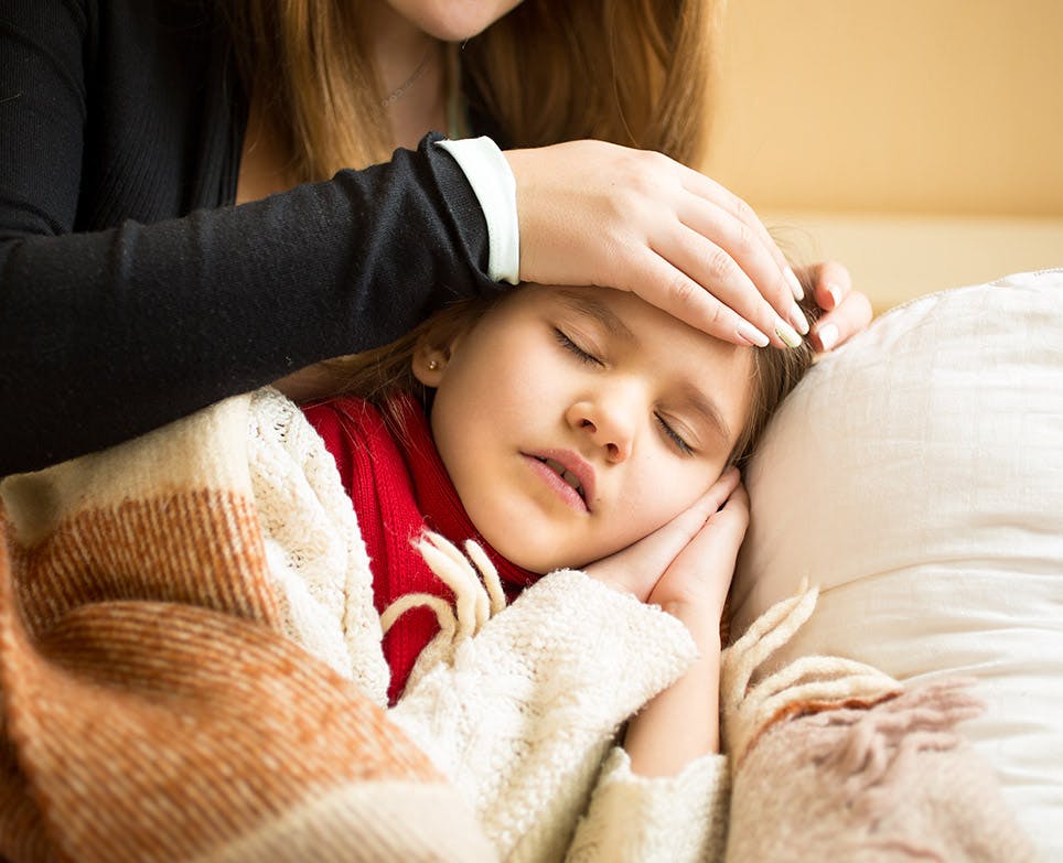 Mother feeling her daughter's temperature by touching her forehead.  