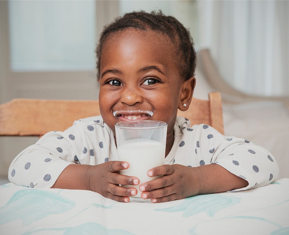 Little girl holding a glass of milk and smiling