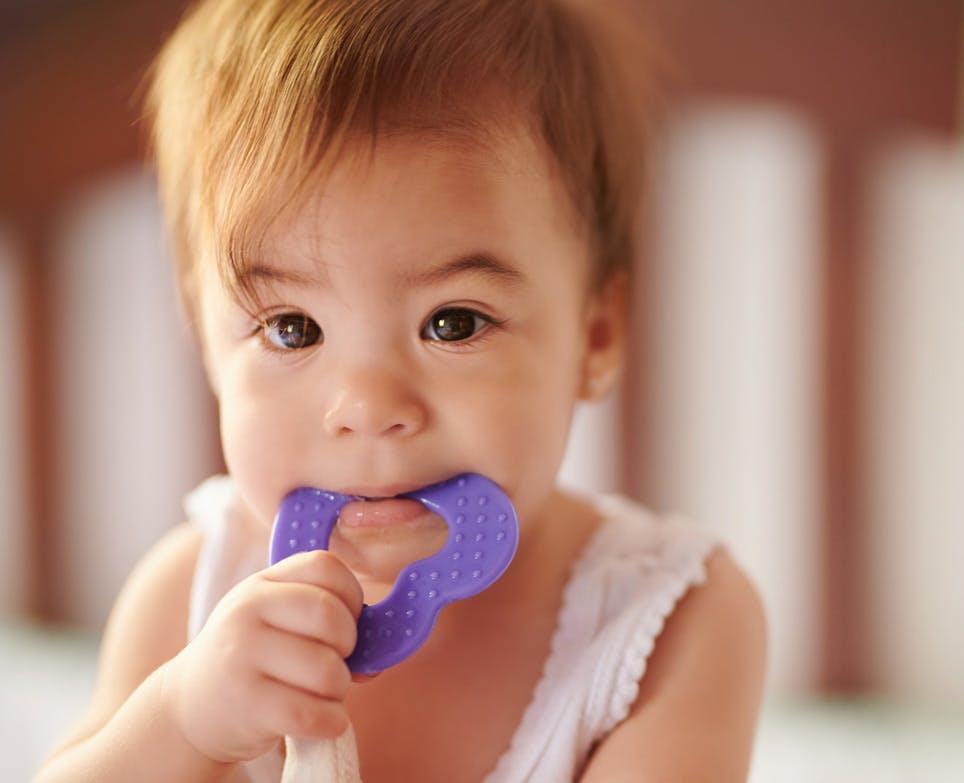 Baby chewing on teething ring toy