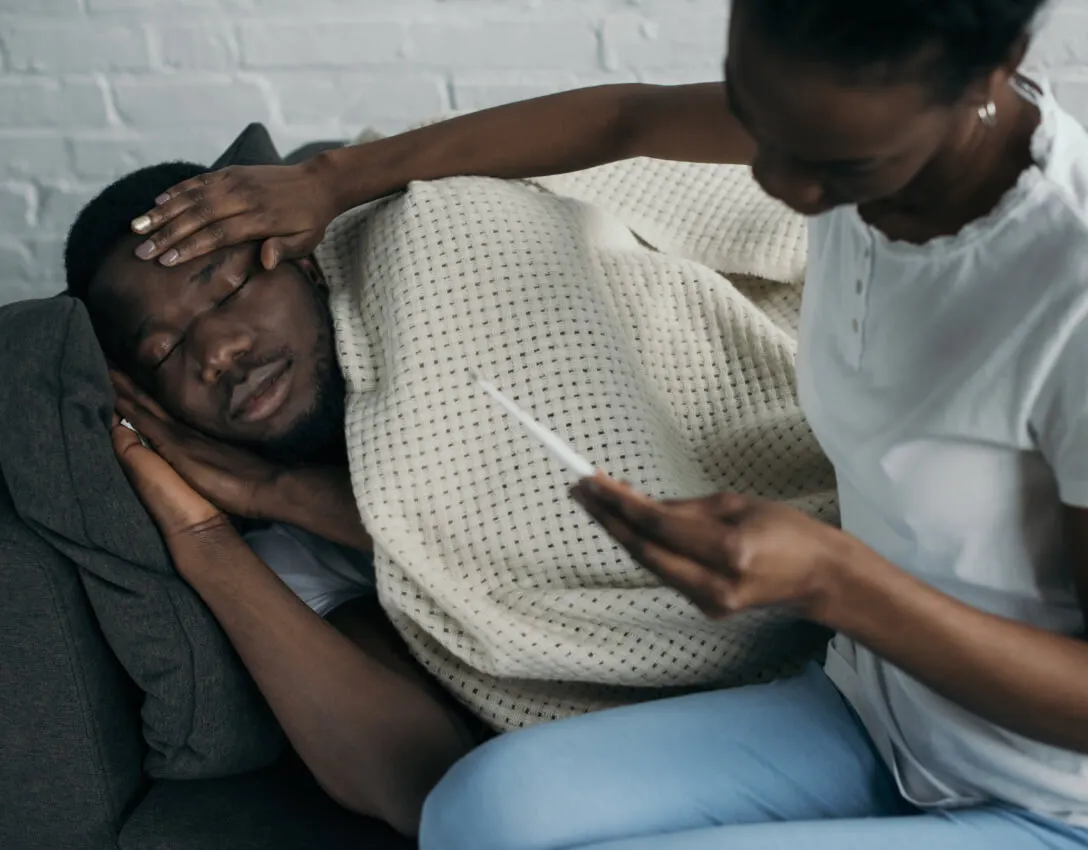 Person lying down looking unwell experiencing fever symptoms